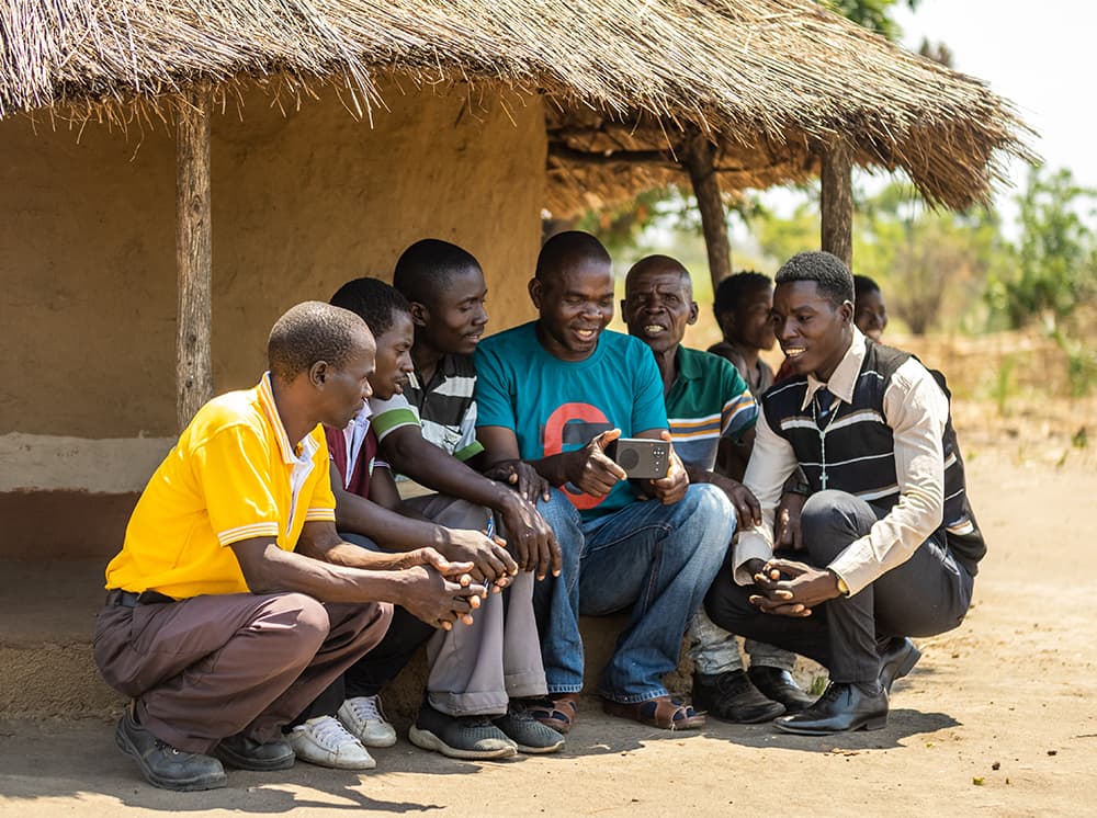 Villagers gathered around an audio device listening to the Bible